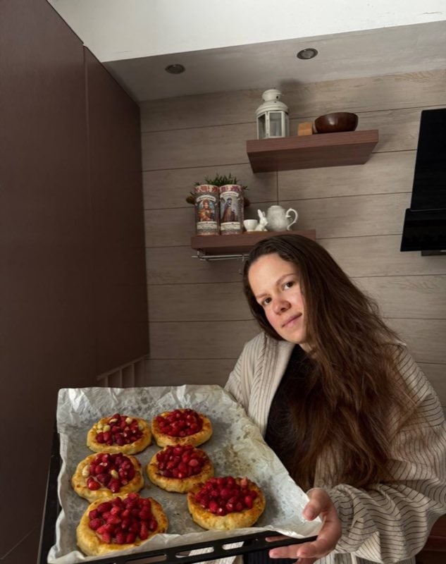 Наталия Махова держит противень с тарталетками с малиной на домашней кухне